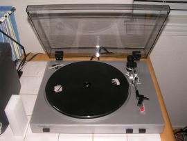 Photo shows a view of the Ion Audio TTUSB05  turntable from above. The cartridge/needle assembly is detached from the tonearm and resting on the body of the record player.